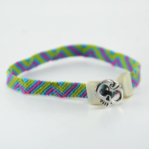 pulsera_hueso_santiago_rugeles_22 Esta **pulsera macrame multicolor** y plata ley 925 destaca por el contraste dinámico de sus tonos y la combinación impecable de materiales. Diseñada y elaborada artesanalmente por Santiago Rugeles, es una joya contemporánea concebida para brindar frescura y personalidad a cualquier estilo. El tejido de esta **pulsera macrame multicolor** resalta por su patrón geométrico en verde manzana, fucsia y azul turquesa, rematado con terminales esculpidas en hueso de res y un distintivo aplique frontal de calavera forjado en plata 925. --- ### Detalles y Especificaciones: * **Materiales:** Hilos de algodón de alta resistencia, aplique central en plata ley 925 y terminales en hueso de res. * **Proceso:** Tejido a mano y ensamblado artesanal, garantizando acabados definidos y durabilidad. * **Estilo:** Unisex / Joyería contemporánea de autor. --- ### Cuidado de tu pieza: Para conservar la viveza de los colores del algodón y el brillo de la plata 925, evita el contacto con perfumes, cremas o lavar la joya con detergentes agresivos.