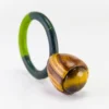 Anillo de autor de ojo de tigre engastado en caja bulbosa de madera de nogal y cedro con aro textil verde.